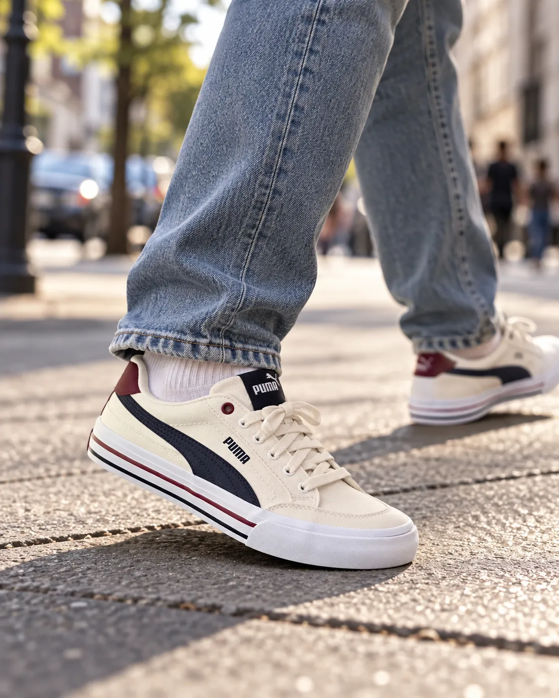 Legs and feet wearing cream Puma sneakers mid-step on a city sidewalk with a blurred street background