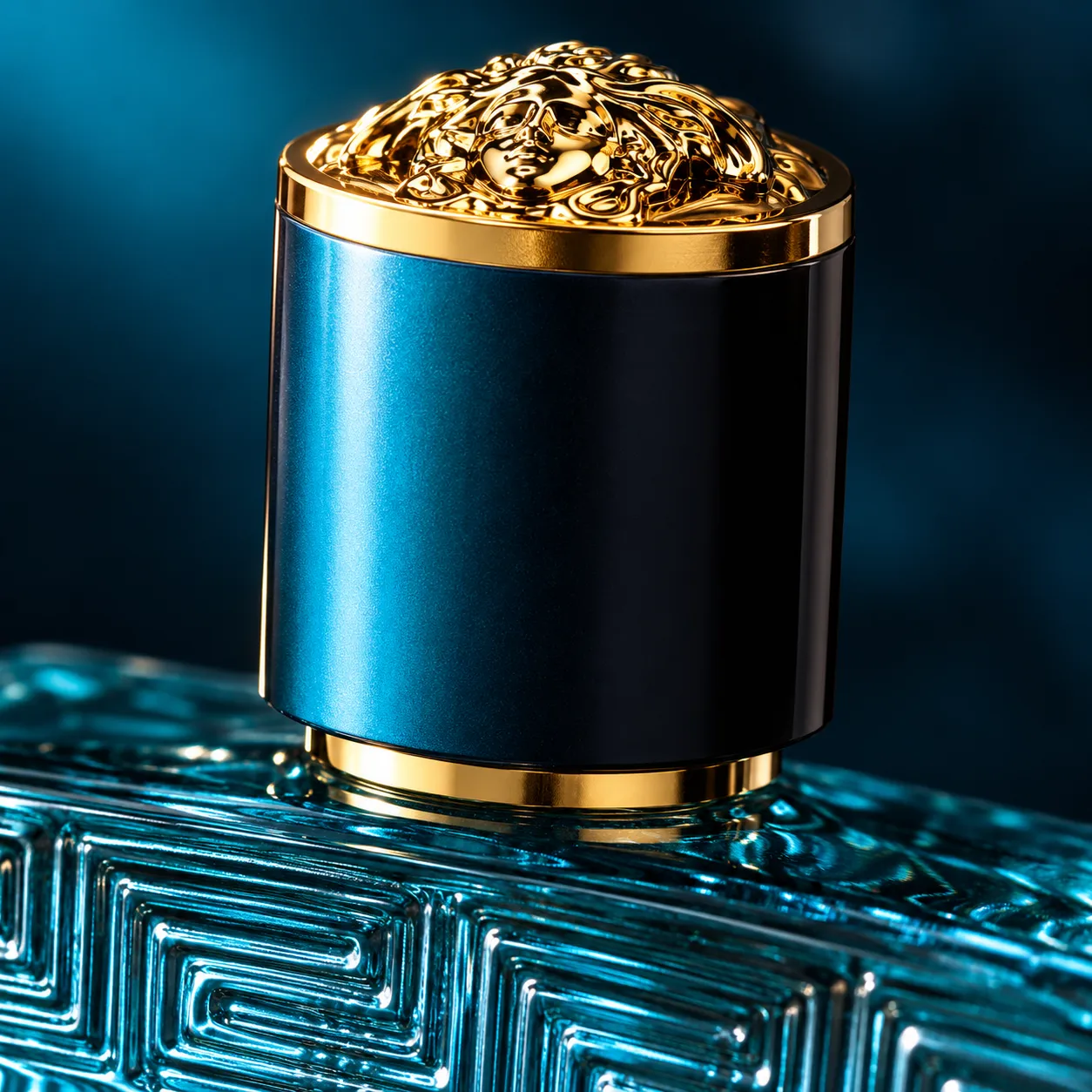 Extreme close-up of a perfume bottle's gold engraved cap and collar