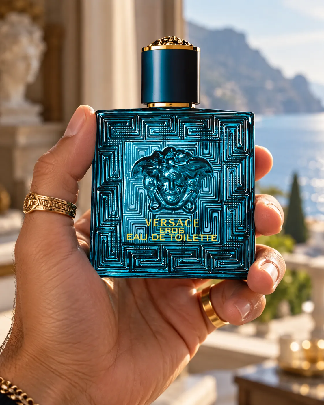 A hand with gold rings holding a perfume bottle up against a scenic outdoor view