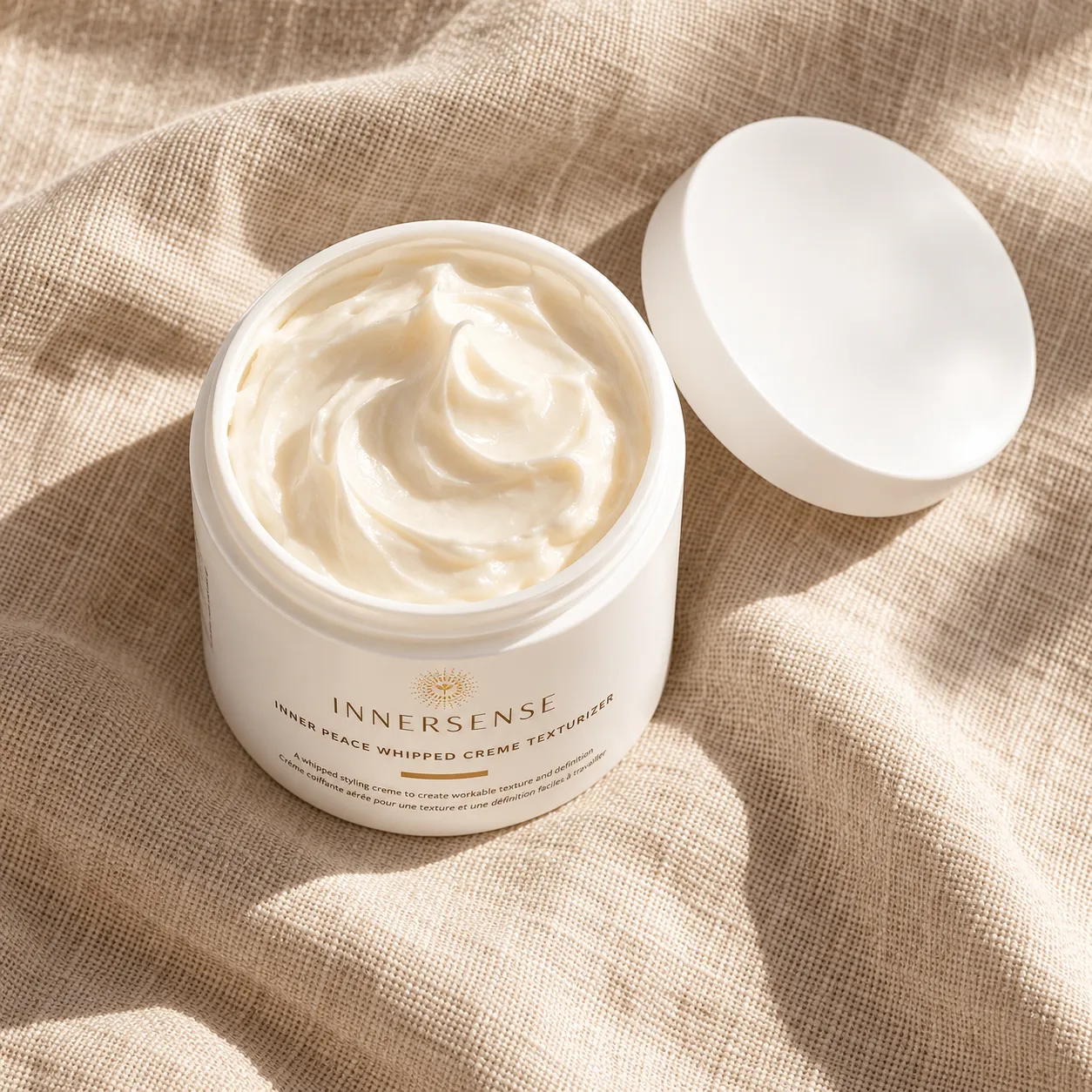 Cream jar with the lid removed and cream visible, placed on a linen surface with a soft shadow, warm afternoon light, top-down angle, shot on a 50mm lens at f/5.6, premium skincare mood, warm amber color grade, commercial product photography, 1:1.