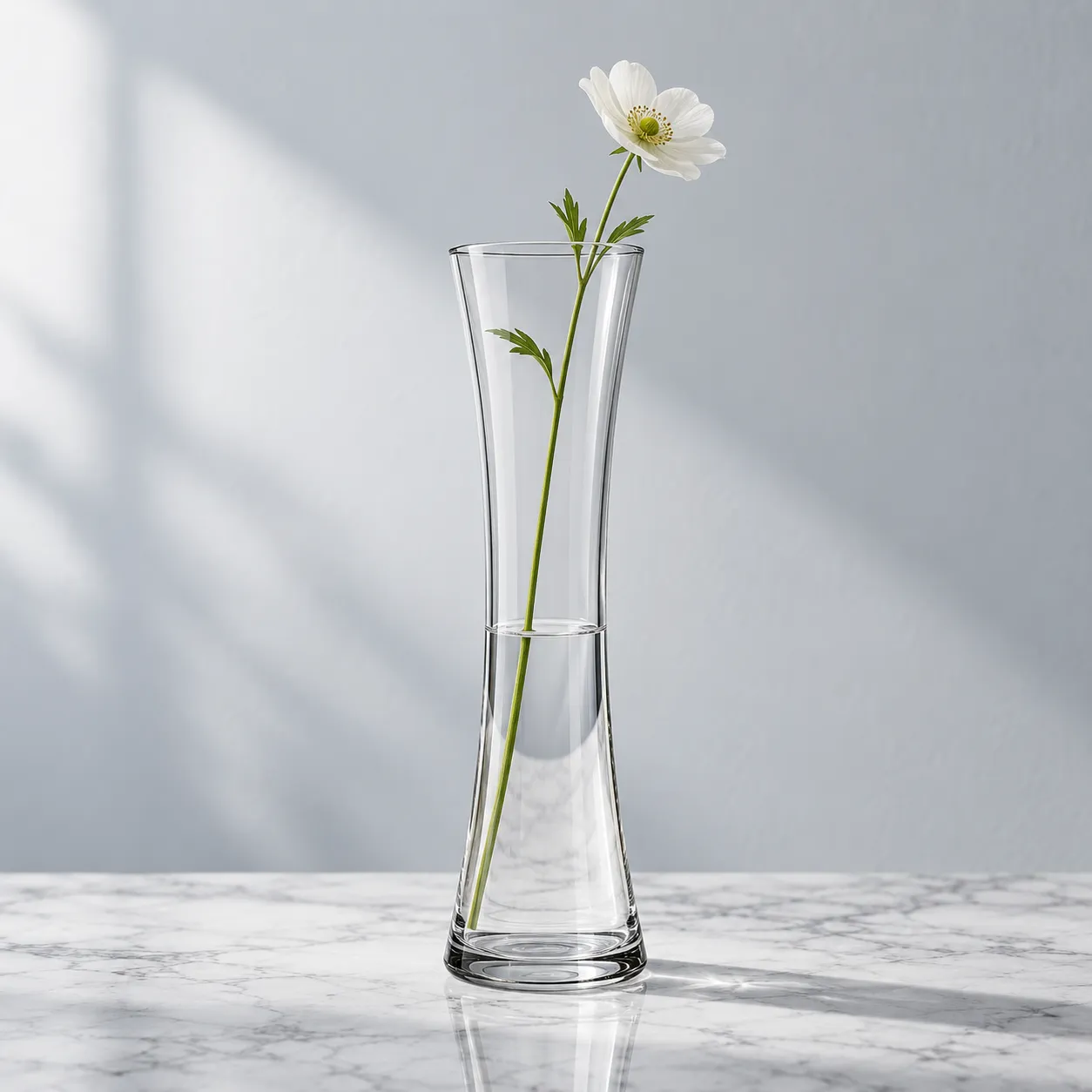 Glass vase with a single stem on a marble shelf, soft diffused daylight, straight-on angle, shot on a 85mm lens at f/5.6, minimal modern mood, cool neutral color grade, commercial product photography, 1:1.